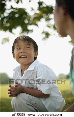 Young boy squatting, looking at his mother View Large Photo Image Stock Photo - Young boy squatting, looking at his mother. Fotosearch