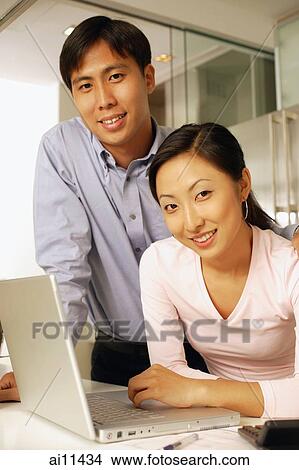 Young couple with laptop, looking at camera View Large Photo Image Picture - Young couple with laptop, looking at camera. Fotosearch