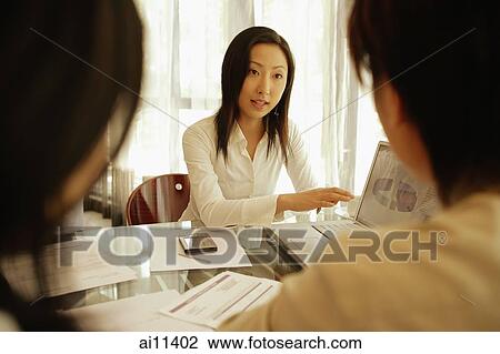 Young female executive using laptop, presenting to colleagues View Large Photo Image Stock Image - Young female executive using laptop, presenting to colleagues. Fotosearch