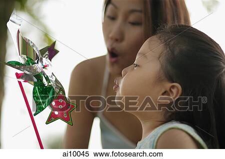 Stock Photography - Young girl and mother blowing a pinwheel. Fotosearch