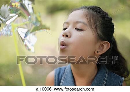 Young girl blowing a pinwheel View Large Photo Image Stock Photograph - Young girl blowing a pinwheel. Fotosearch
