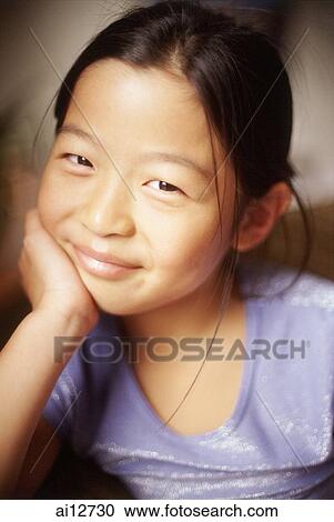 Stock Image - Young girl, hand on chin, looking at camera. Fotosearch