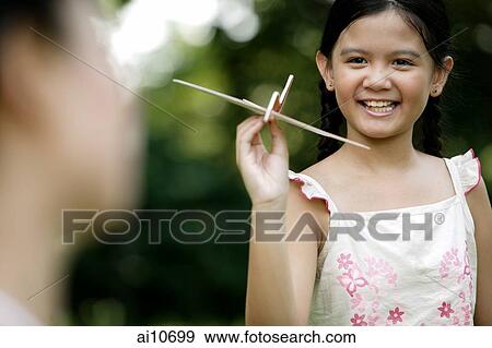 Stock Photo - Young girl holding a paper airplane, mother in the foreground. Fotosearch