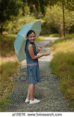 Young girl holding an umbrella, looking over shoulder View Large Photo Image Stock Photograph - Young girl holding an umbrella, looking over shoulder. Fotosearch