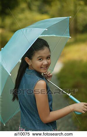 Young girl holding an umbrella, looking over shoulder View Large Photo Image Stock Photography - Young girl holding an umbrella, looking over shoulder. Fotosearch