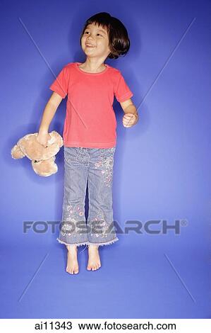Young girl jumping, holding teddy bear View Large Photo Image Stock Image - Young girl jumping, holding teddy bear. Fotosearch