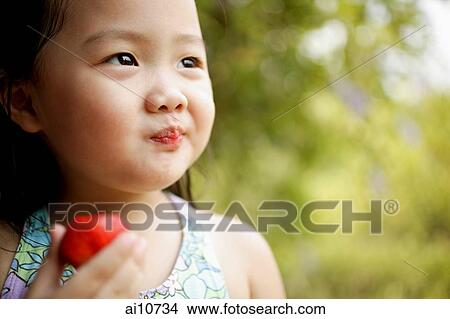 Young girl looking away, holding plum View Large Photo Image Picture - Young girl looking away, holding plum. Fotosearch