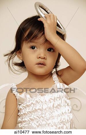 Young girl looking away, holding up her costume halo. View Large Photo Image Stock Photo - Young girl looking away, holding up her costume halo.. Fotosearch