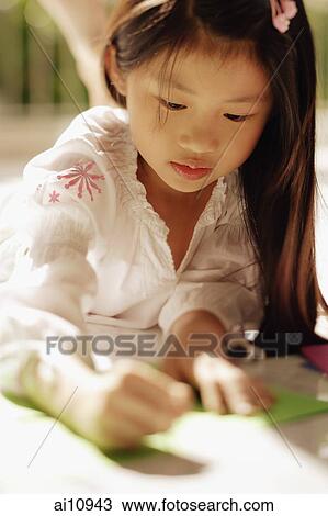 Stock Image - Young girl looking down, writing. Fotosearch