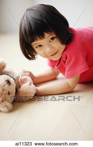 Young girl lying on front, holding teddy bear View Large Photo Image Stock Image - Young girl lying on front, holding teddy bear. Fotosearch