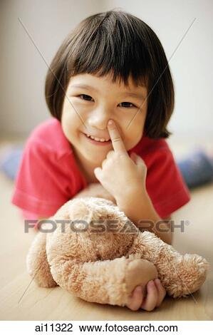 Young girl lying on front, touching her nose View Large Photo Image Stock Image - Young girl lying on front, touching her nose. Fotosearch