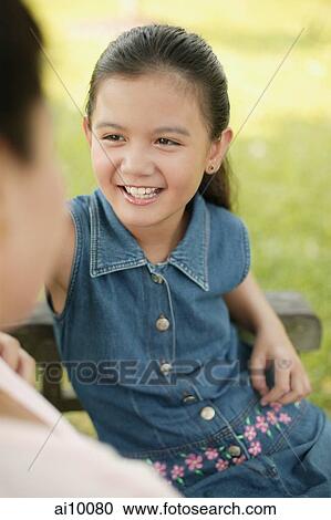 Stock Image - Young girl sitting down with her mother. Fotosearch
