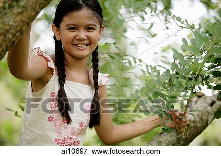 Young girl sitting in tree, smiling at camera View Large Photo Image Stock Photo - Young girl sitting in tree, smiling at camera. Fotosearch