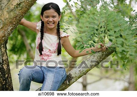 Young girl sitting in tree, smiling at camera View Large Photo Image Stock Photo - Young girl sitting in tree, smiling at camera. Fotosearch