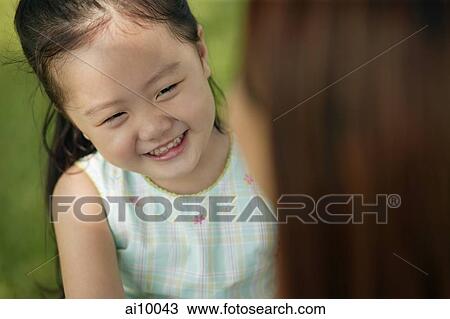 Young girl smiling, mother looking on View Large Photo Image Stock Image - Young girl smiling, mother looking on. Fotosearch
