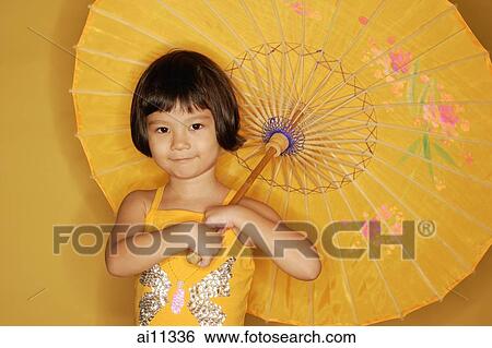 Young girl standing against yellow background, holding umbrella View Large Photo Image Stock Photograph - Young girl standing against yellow background, holding umbrella. Fotosearch