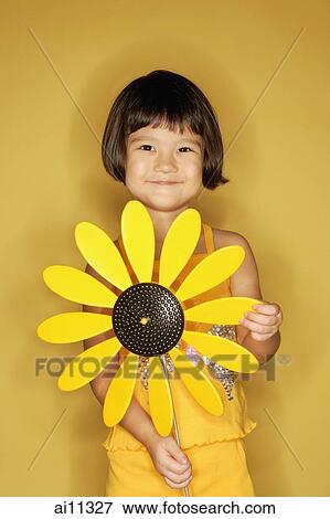 Young girl standing holding plastic sunflower. View Large Photo Image Stock Photo - Young girl standing holding plastic sunflower.. Fotosearch