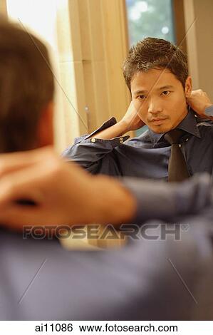Young man adjusting tie and collar, looking in mirror View Large Photo Image Stock Photograph - Young man adjusting tie and collar, looking in mirror. Fotosearch