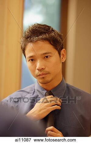 Young man adjusting tie, looking in mirror View Large Photo Image Stock Photo - Young man adjusting tie, looking in mirror. Fotosearch