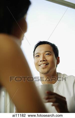 Young man and woman talking, man holding coffee cup View Large Photo Image Stock Image - Young man and woman talking, man holding coffee cup. Fotosearch