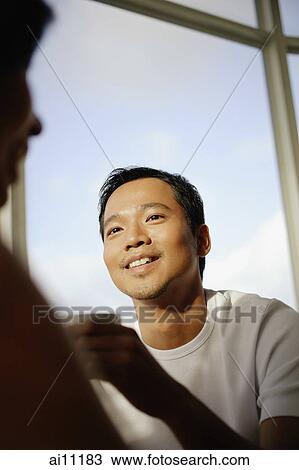 Stock Image - Young man and woman talking, man holding coffee cup. Fotosearch