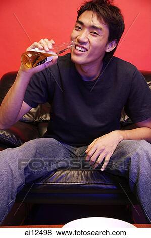 Young man drinking from beer bottle, looking at camera View Large Photo Image Stock Photo - Young man drinking from beer bottle, looking at camera. Fotosearch