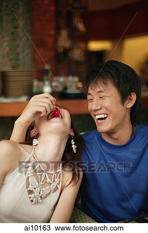Stock Image - Young man feeding young woman a cherry. Fotosearch