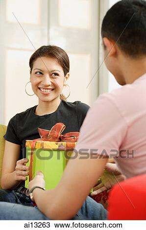 Young man giving gift box to young woman View Large Photo Image Stock Image - Young man giving gift box to young woman. Fotosearch