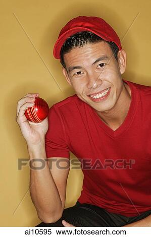 Young man holding a ball, yellow background View Large Photo Image Stock Photography - Young man holding a ball, yellow background. Fotosearch