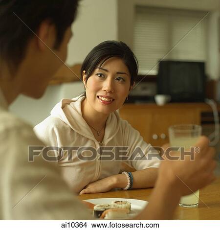 Young man holding a glass, woman looking at him. View Large Photo Image Picture - Young man holding a glass, woman looking at him.. Fotosearch