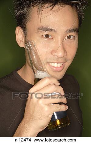 Young man holding beer bottle, looking at camera View Large Photo Image Picture - Young man holding beer bottle, looking at camera. Fotosearch
