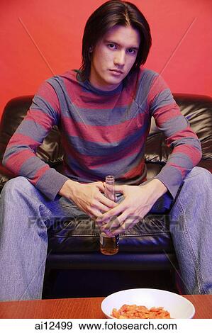 Young man holding beer bottle, looking at camera View Large Photo Image Stock Photo - Young man holding beer bottle, looking at camera. Fotosearch