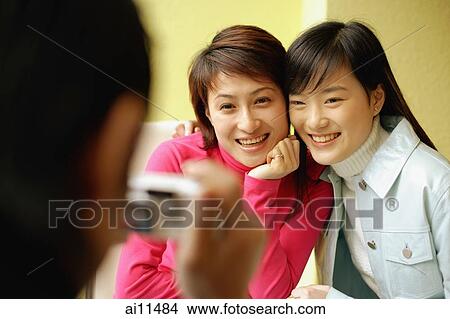 Young man holding camera, two women posing for picture View Large Photo Image Picture - Young man holding camera, two women posing for picture. Fotosearch