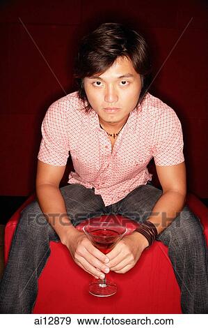 Young man holding drink, looking at camera View Large Photo Image Stock Photo - Young man holding drink, looking at camera. Fotosearch