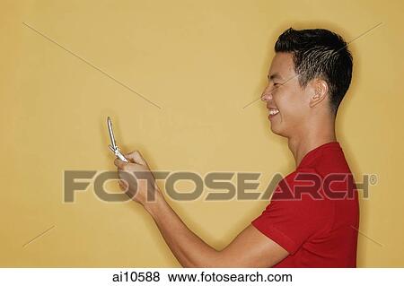 Young man holding mobile phone, profile View Large Photo Image Stock Photo - Young man holding mobile phone, profile. Fotosearch