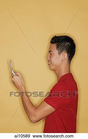 Young man holding mobile phone, profile View Large Photo Image Stock Photo - Young man holding mobile phone, profile. Fotosearch