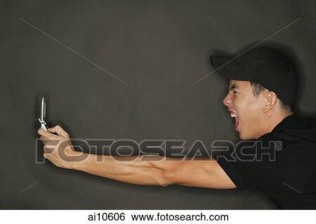Stock Photograph - Young man holding mobile phone, profile. Fotosearch