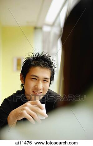 Stock Photograph - Young man holding teacup, facing young woman. Fotosearch