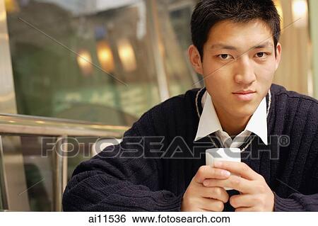 Young man holding teacup, looking at camera View Large Photo Image Stock Photograph - Young man holding teacup, looking at camera. Fotosearch