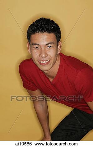 Young man leaning forward, smiling at camera View Large Photo Image Stock Photograph - Young man leaning forward, smiling at camera. Fotosearch