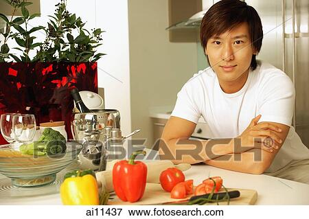 Young man leaning on kitchen counter, arms crossed View Large Photo Image Stock Photo - Young man leaning on kitchen counter, arms crossed. Fotosearch