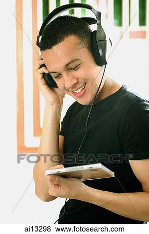Stock Photo - Young man listening to music, wearing headphones. Fotosearch