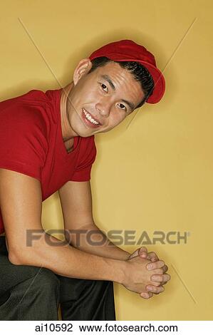Young man looking at camera, leaning forward, hands clasped View Large Photo Image Stock Image - Young man looking at camera, leaning forward, hands clasped. Fotosearch