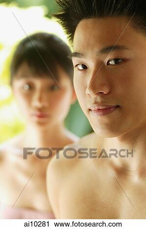 Stock Image - Young man looking at camera, woman in the foreground. Fotosearch