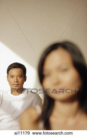 Young man looking at camera, woman in front of him View Large Photo Image Stock Photo - Young man looking at camera, woman in front of him. Fotosearch