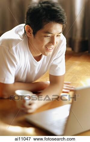 Stock Photo - Young man looking at laptop,. Fotosearch