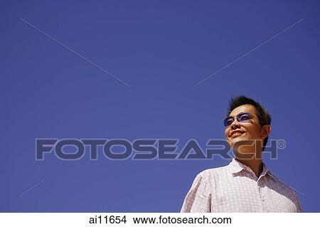 Picture - Young man looking away, low angle view. Fotosearch