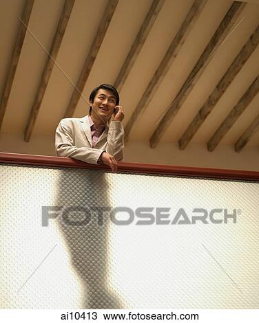 Young man on mobile phone, low angle view View Large Photo Image Stock Image - Young man on mobile phone, low angle view. Fotosearch