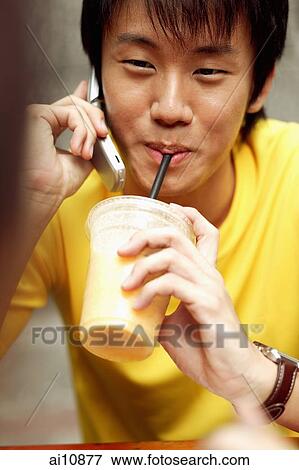 Young man on the phone, holding cup and drinking too. View Large Photo Image Stock Photo - Young man on the phone, holding cup and drinking too.. Fotosearch