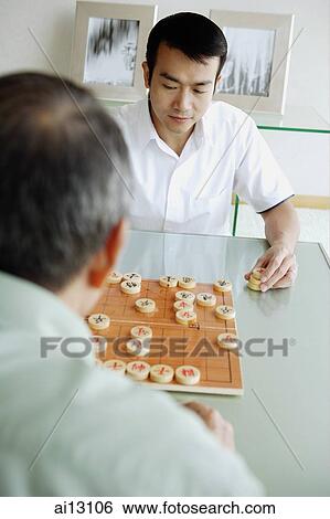 Young man playing Chinese chess with older man View Large Photo Image Stock Photograph - Young man playing Chinese chess with older man. Fotosearch
